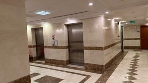 A hallway with elevators and a fire exit sign. - Radwan Al Diyafah Hotel  (Makkah)