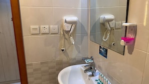 A bathroom with a sink, two hair dryers mounted on the wall, a mirror, and a soap dispenser. - Radwan Al Diyafah Hotel  (Makkah)