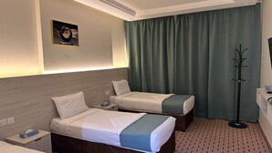 A hotel room with two beds, a coat rack, and a framed picture on the wall. - Radwan Al Diyafah Hotel  (Makkah)