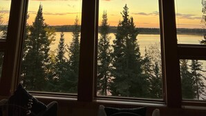 A room with large windows overlooking a lake and forest at sunset. - Bay Ridge North Lakeshore Lodge Retreat (Park Rapids)