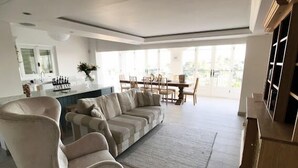 Una sala de estar moderna con un sofá modular, un comedor y una cocina al fondo.