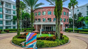 A hotel with a curved facade, a central fountain, and a well-maintained garden with palm trees and shrubs.