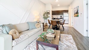 A modern living room with a sofa, coffee table, and dining area.