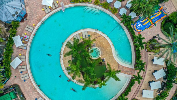 A large circular pool with a central island, surrounded by lounge areas and umbrellas.