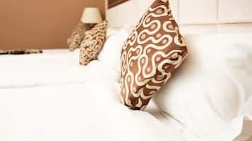 A bed with white bedding and patterned pillows, a bedside lamp, and a headboard.