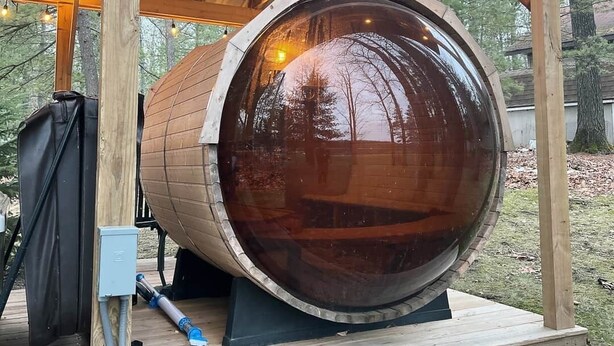 A large wooden barrel structure with a glass dome, surrounded by a wooden deck and a covered area with string lights. - 4-bedroom two level guest house next to Shupac Lake in Grayling (Grayling)