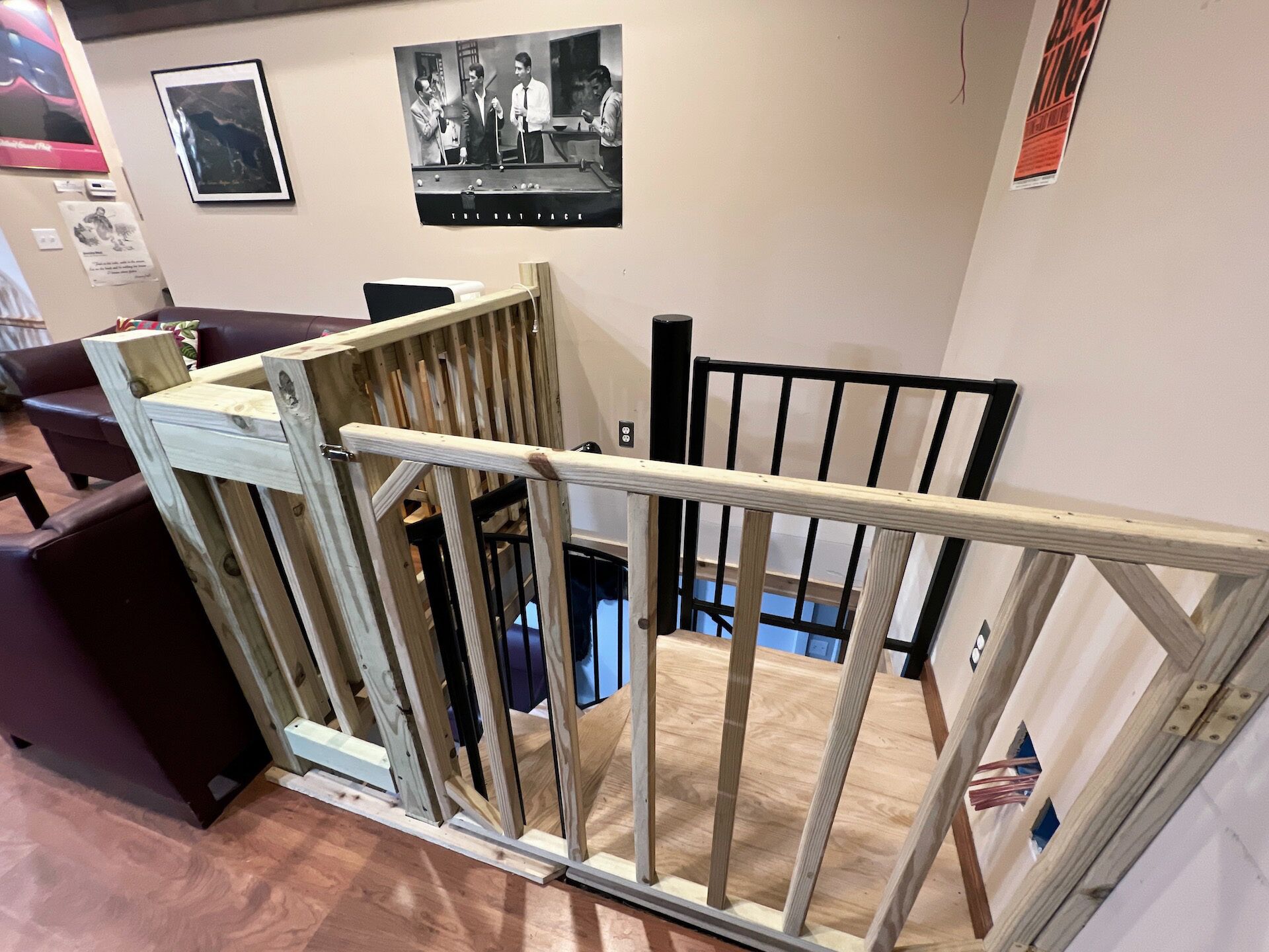 A room with a wooden playpen structure, a pool table, and a poster on the wall.