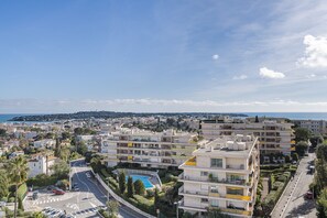 Un quartier résidentiel situé sur la côte, avec des immeubles d’appartements, une piscine et une vue dégagée sur la mer.