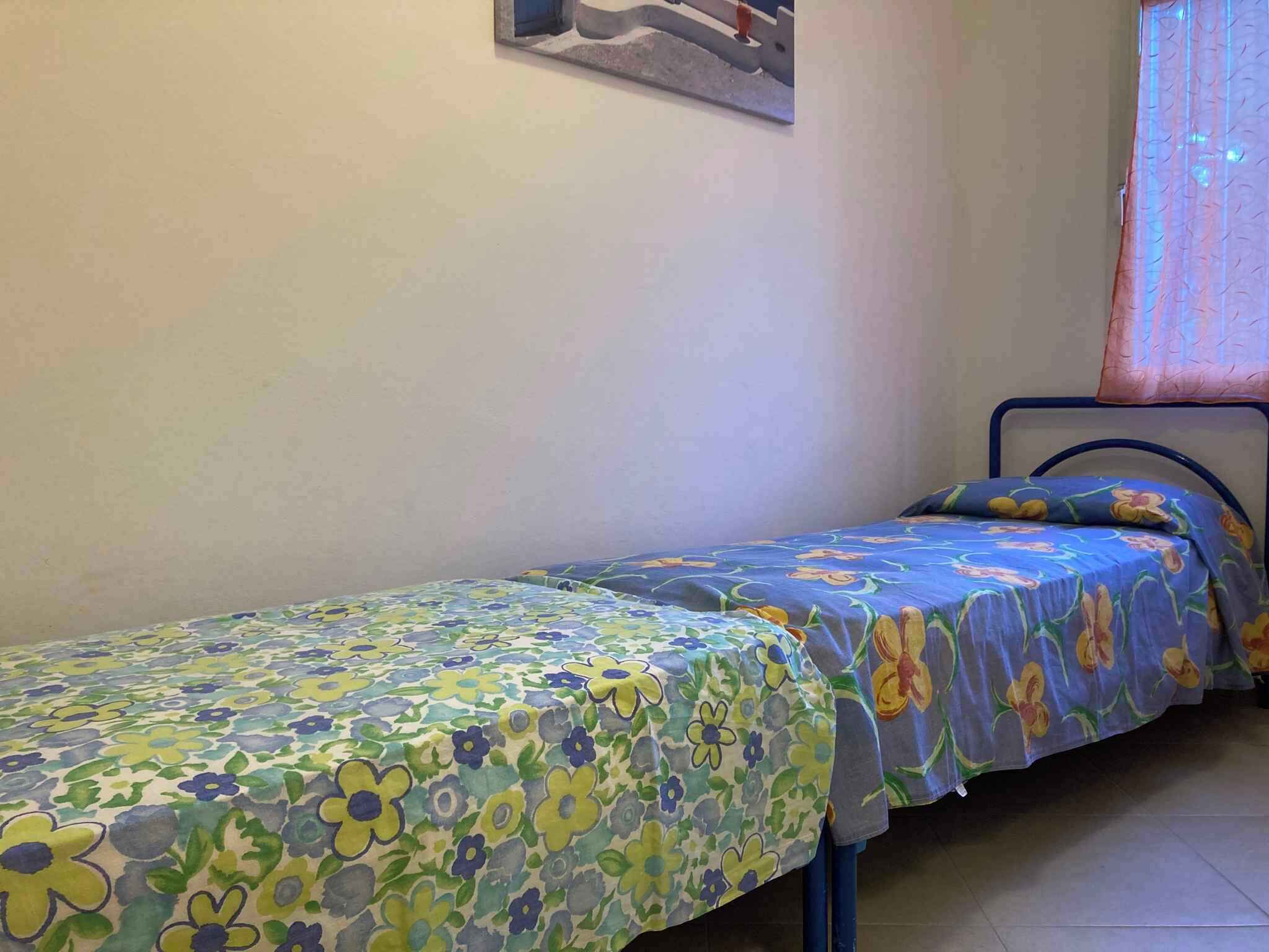 A small, single-bed room with a floral bedspread and a metal bed frame.