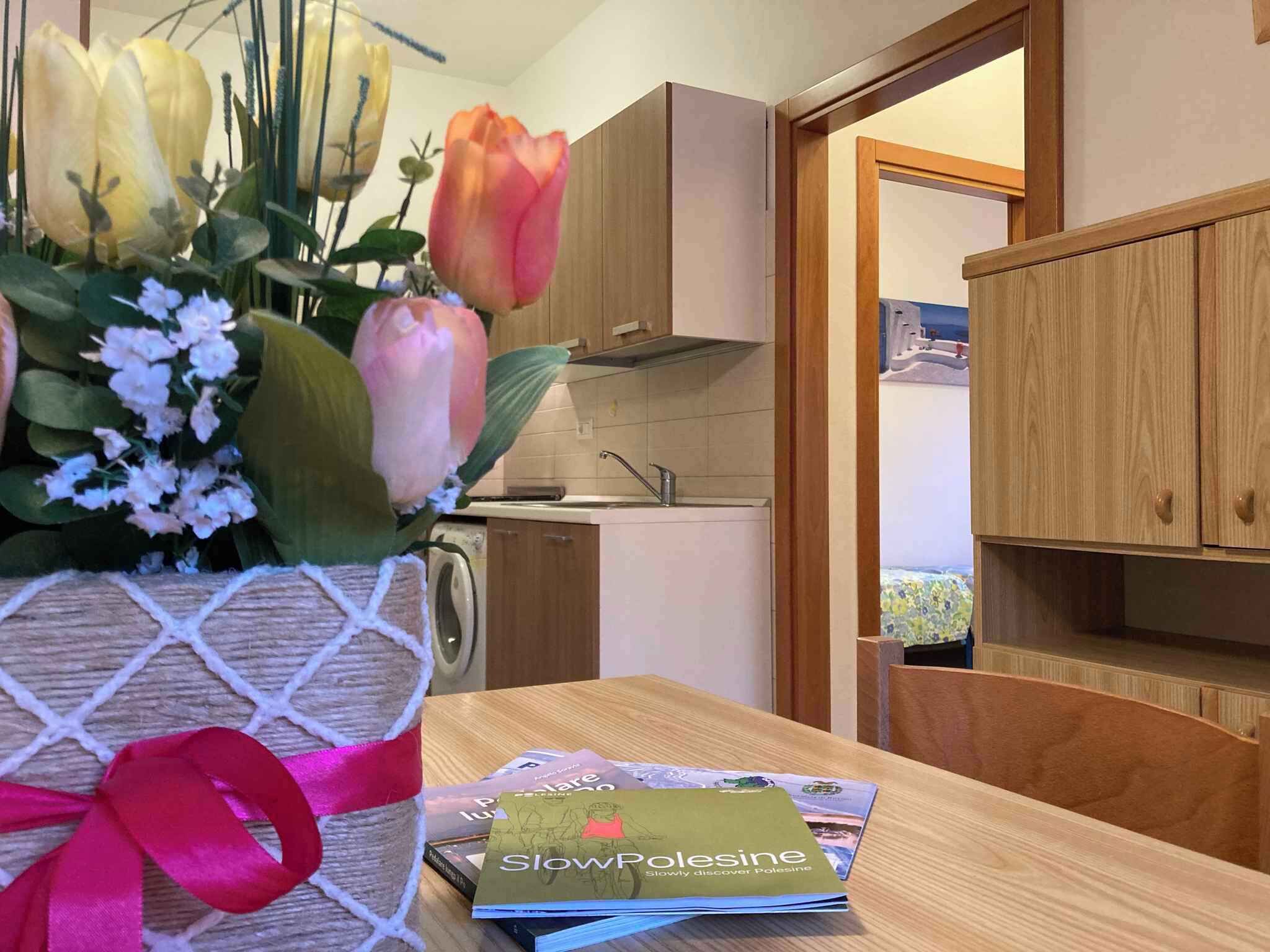 A kitchen with wooden cabinets, a sink, and a vase with flowers on the table.