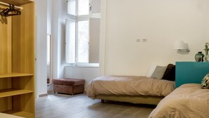 Ein Schlafzimmer mit zwei Betten, einem Holzschrank, einem Fenster und einem Nachttisch mit Lampe.