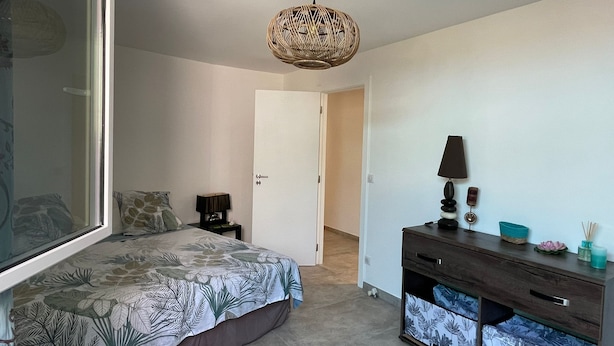 Une chambre à coucher comprenant un lit, une table de chevet, une commode et un luminaire suspendu.