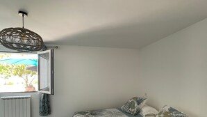 Une chambre à coucher avec un lit, une fenêtre, un radiateur et un luminaire suspendu.
