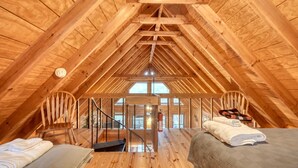 Ein Schlafzimmer im Dachgeschoss mit Holzbalken, einer Treppe und einem Bett mit Decke.