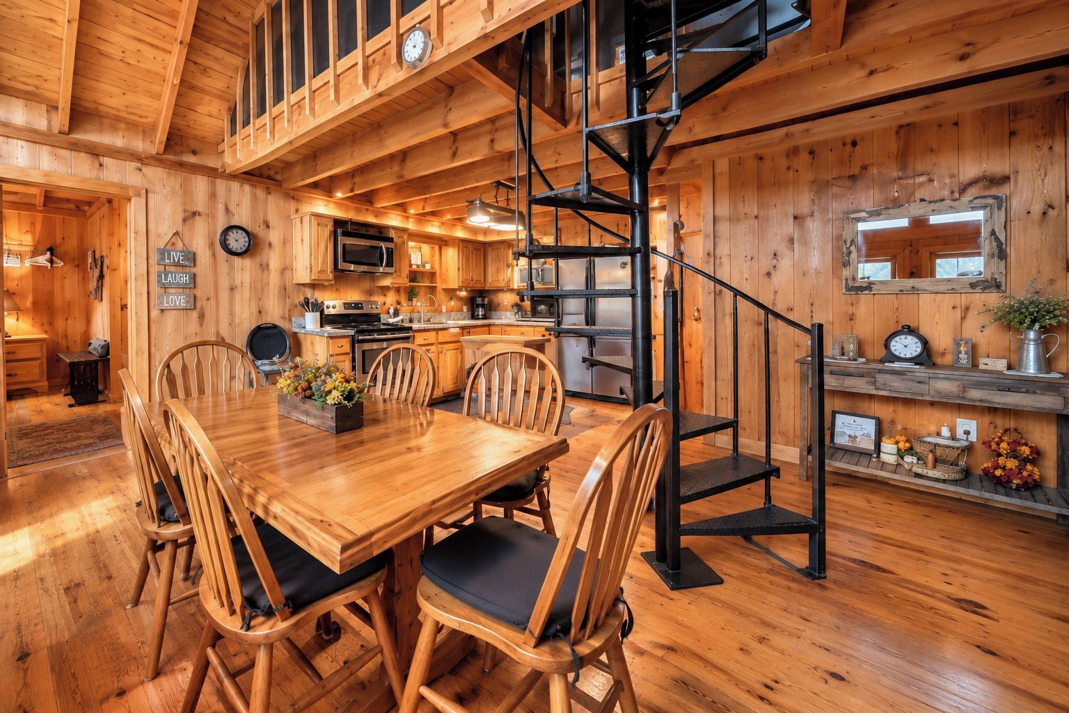 Un intérieur en bois comprenant un coin repas, une cuisine et un escalier en colimaçon.