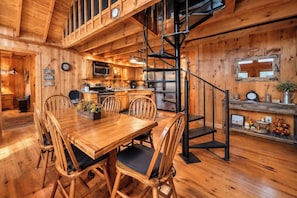 Un intérieur en bois comprenant un coin repas, une cuisine et un escalier en colimaçon.
