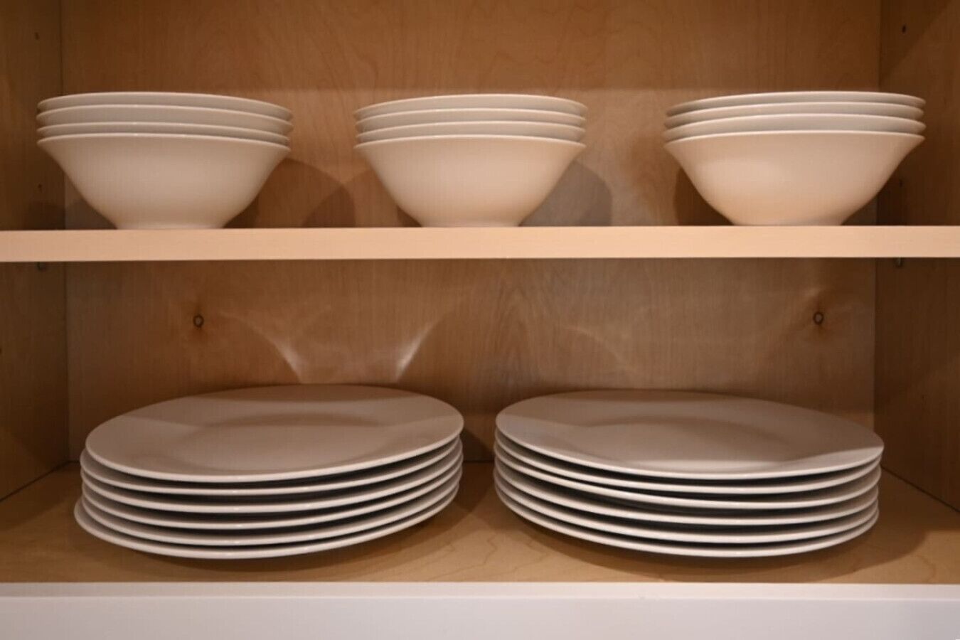Un área de almacenamiento con estantes que contienen pilas de cuencos y platos blancos.