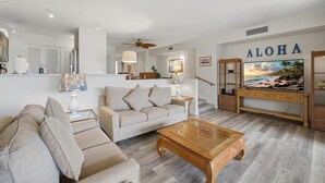 Ein Wohnzimmer mit einer Couch, einem Couchtisch und einem Fernseher, der 'ALOHA' anzeigt.