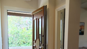 A hallway with a wooden door, a glass door, and a view of greenery outside. - Helle Wohnung mit Balkon im Grünen in Strandnähe (La Croix-Valmer)