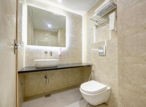 A modern bathroom with a white sink, a toilet, and a shower area.