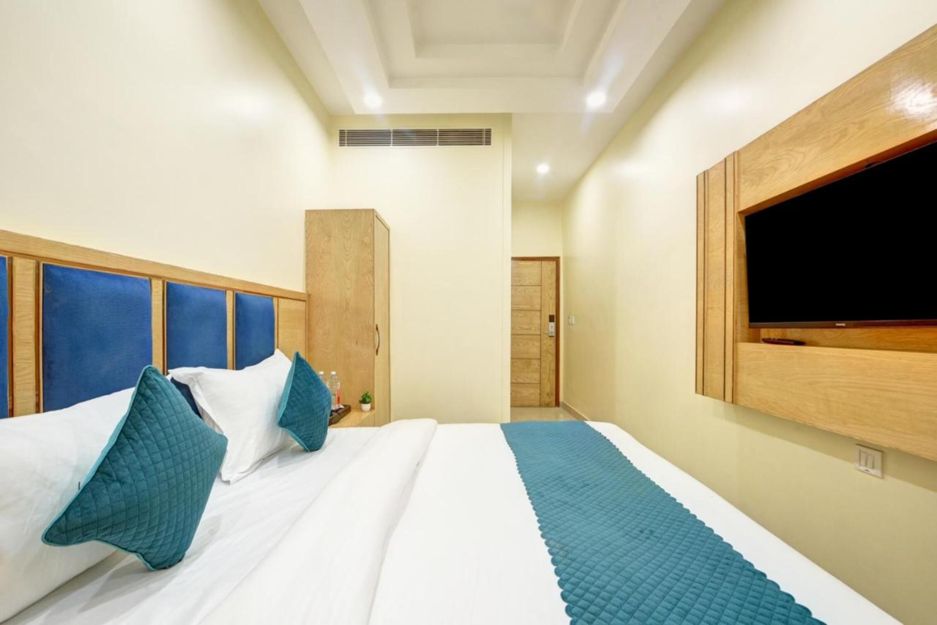 A hotel room with a large bed, a TV mounted on the wall, and a wardrobe.