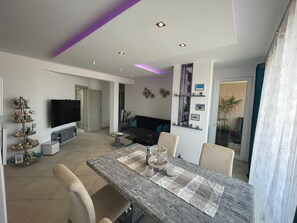 Relax in this stylish living room with a flat-screen TV, dining area, and comfortable sofa.