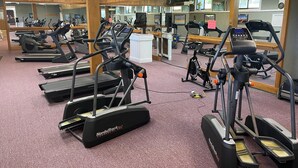 Un gimnasio con cintas de correr, bicicletas estáticas y equipo de ejercicio.