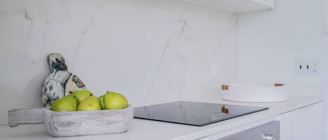 A kitchen with a marble countertop, a bowl of fruit, a cutting board, and an oven.