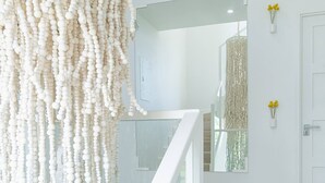 Una escalera con barandilla blanca que lleva a una habitación con pared blanca y un adorno colgante.
