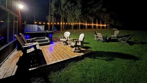 An outdoor deck with a barbecue area, seating, and string lights. - Modern Rustic Retreat- King bed, hot tub, wineries, waterfalls, hiking, Cornell (Ithaca)