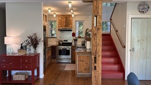 A kitchen with wooden cabinets, a stove, and a sink. There is a staircase leading to a second floor. - Modern Rustic Retreat- King bed, hot tub, wineries, waterfalls, hiking, Cornell (Ithaca)