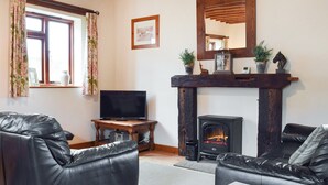 A cozy living room with leather sofas, a flat-screen TV, a fireplace, and a wooden mantelpiece. - The Old Stable - Meadowbrook Farm (Moreton, near Thame)