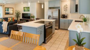 A modern kitchen with a central island, stainless steel appliances, and light blue cabinetry. - Mauka Sunrise, Walk to Hau‘ula Beach & Trails, A/C (Hauula)