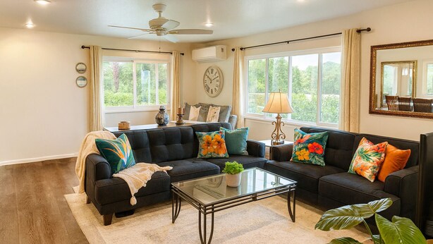 A living room with a sectional sofa, a glass coffee table, and a ceiling fan. - Mauka Sunrise, Walk to Hau‘ula Beach & Trails, A/C (Hauula)