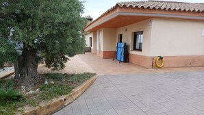 A building with a tiled roof, a covered outdoor area, and a tree.