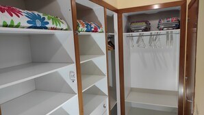 A walk-in closet with open shelves, a hanging rod, and a door with a mirror.