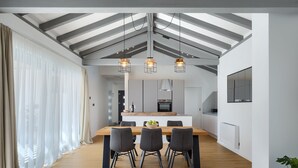 A modern kitchen with a central island, pendant lights, and a dining area with a wooden table and chairs.