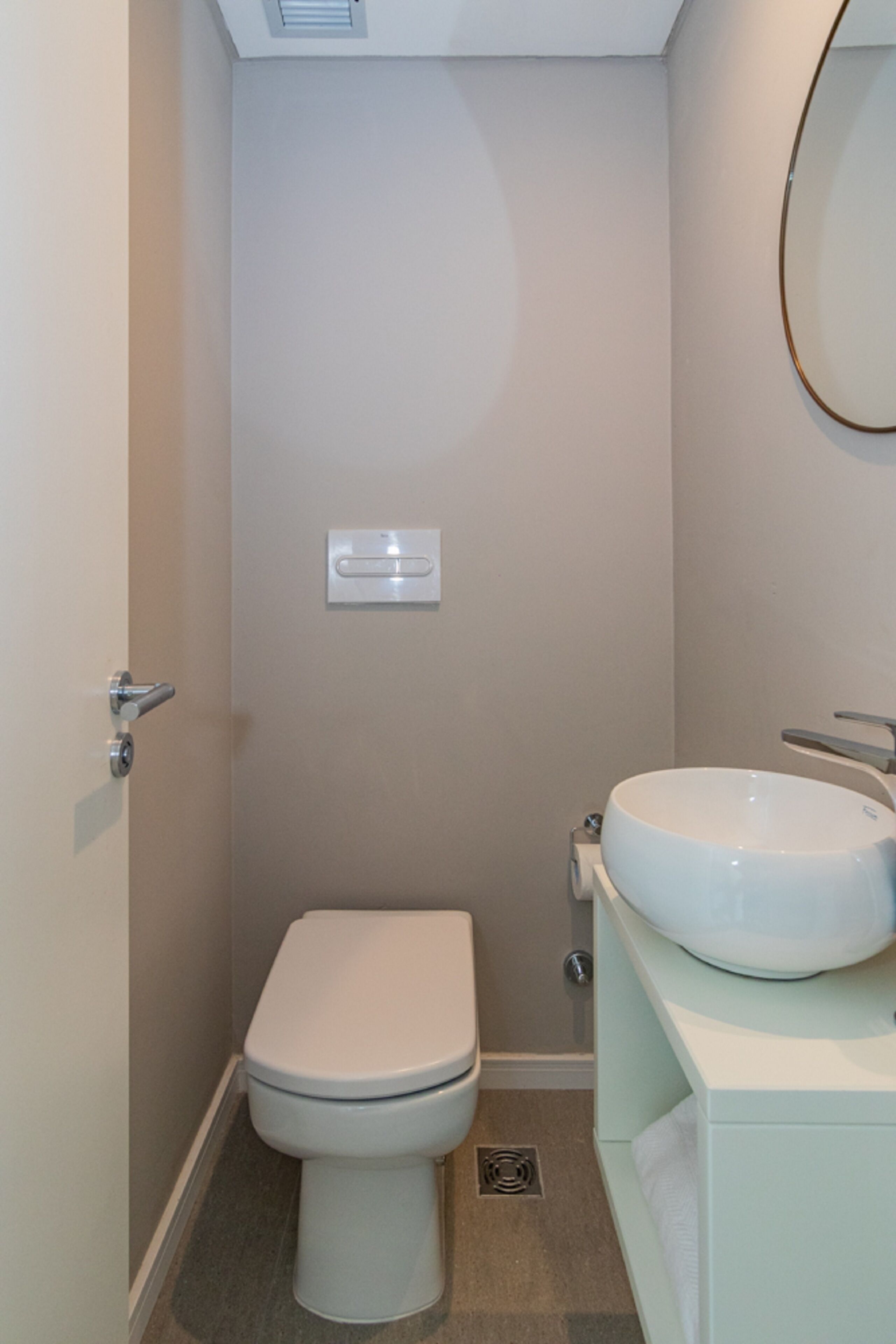 Un baño pequeño y moderno con inodoro, lavabo y espejo.