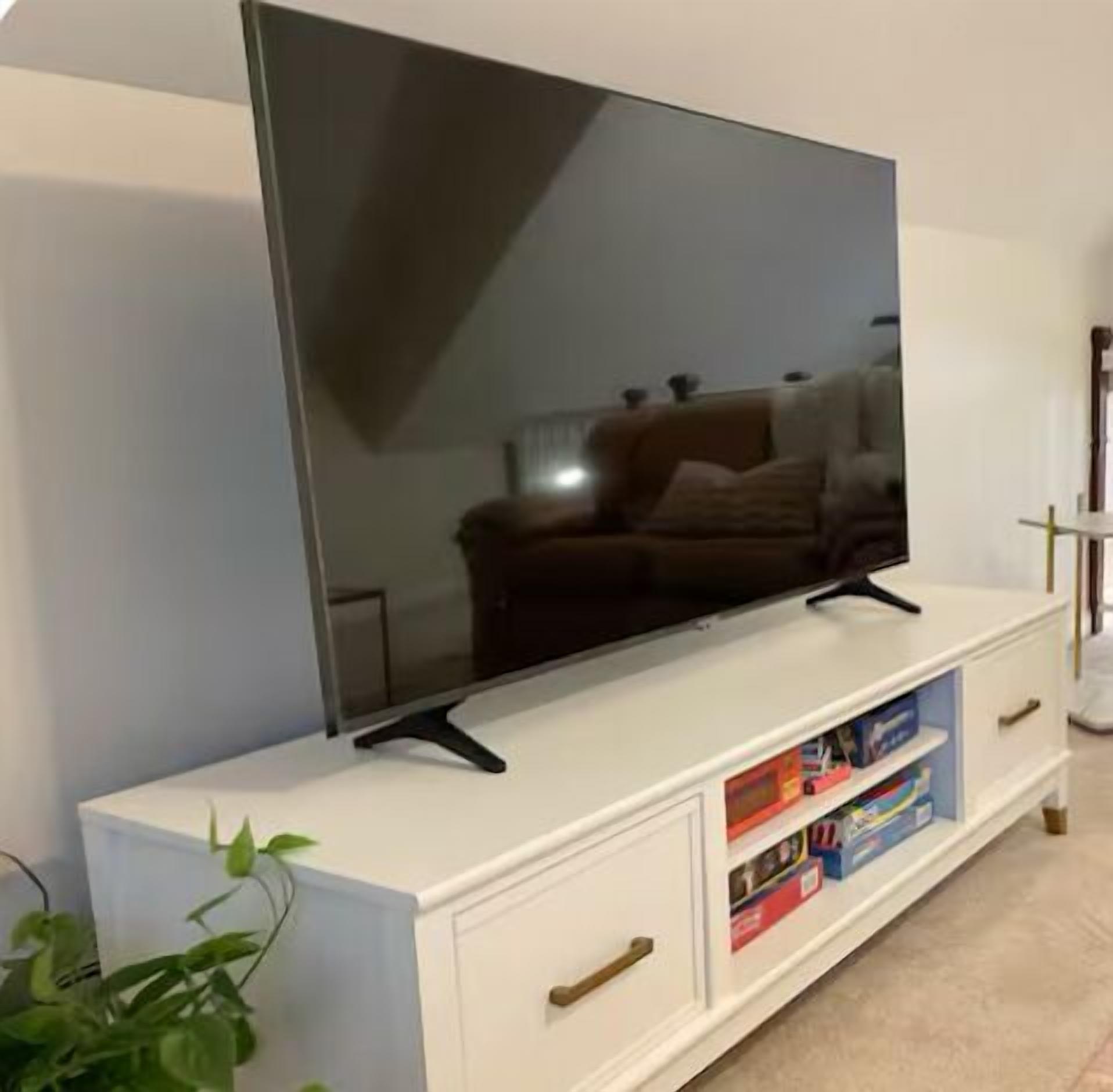Una TV a schermo piatto su un mobile bianco contenitore con cassetti e ripiani.
