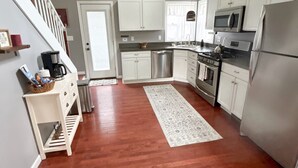 Une cuisine moderne avec des meubles blancs, des appareils électroménagers en acier inoxydable et un plancher en bois.