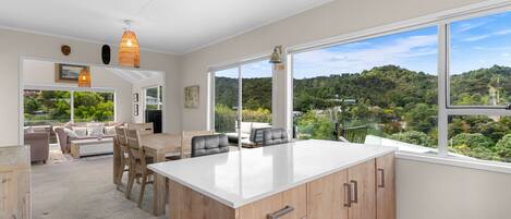 Una cocina moderna con una isla grande, armarios de madera y vistas a un paisaje verde y exuberante.