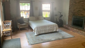 A bedroom with a bed, a chair, a fireplace, and a ceiling fan. - Spacious 6BR, 10 bed Derby House. Walk to the track. (Louisville)