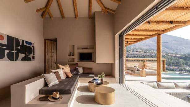 A modern living room with a sofa, coffee table, and a view of a mountainous landscape through an open space. - Ionian residence  (Kefalonia)