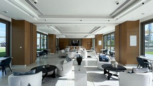 A spacious lobby with modern furniture, large windows, and a view of the city.