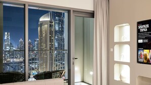 A modern hotel room with a city view, a large sliding glass door, and a poster on the wall.