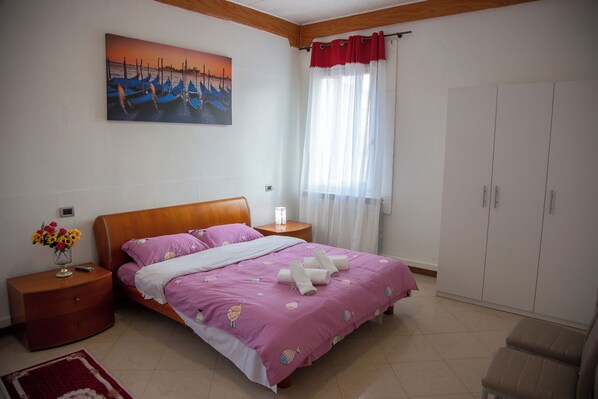 A bedroom with a bed, nightstands, a dresser, a wardrobe, a painting, and a window with curtains.