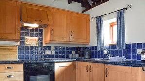 A kitchen with wooden cabinets, a black oven, and a tiled backsplash. - Byre Cottage - Meadowbrook Farm (Moreton, near Thame)