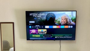 Seinälle asennettu televisio, jonka näytöllä näkyy suoratoistopalvelun käyttöliittymä, jossa on useita eri elokuvavaihtoehtoja.