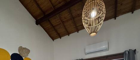Una habitación con dos camas, techo de madera, lámpara colgante y vistas a través de un ventanal.