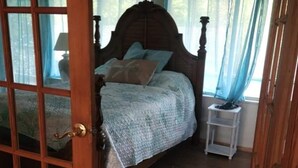 Ein Schlafzimmer mit einem hölzernen Bett, einem Nachttisch und einem Fenster mit blauen Vorhängen.